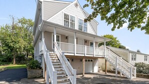 Une maison à deux étages avec un porche avant couvert, un escalier menant à l’étage supérieur et un garage.