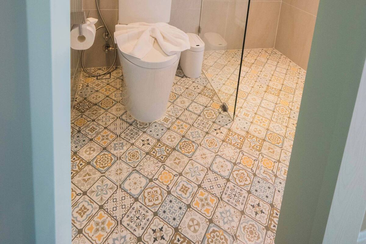 Une salle de bain avec des toilettes, une douche et des carreaux de sol à motifs.