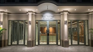 A hotel entrance with double doors, columns, and a sign above the doors. - TUAN Hotel Bangkok near Wat Arun (Bangkok)