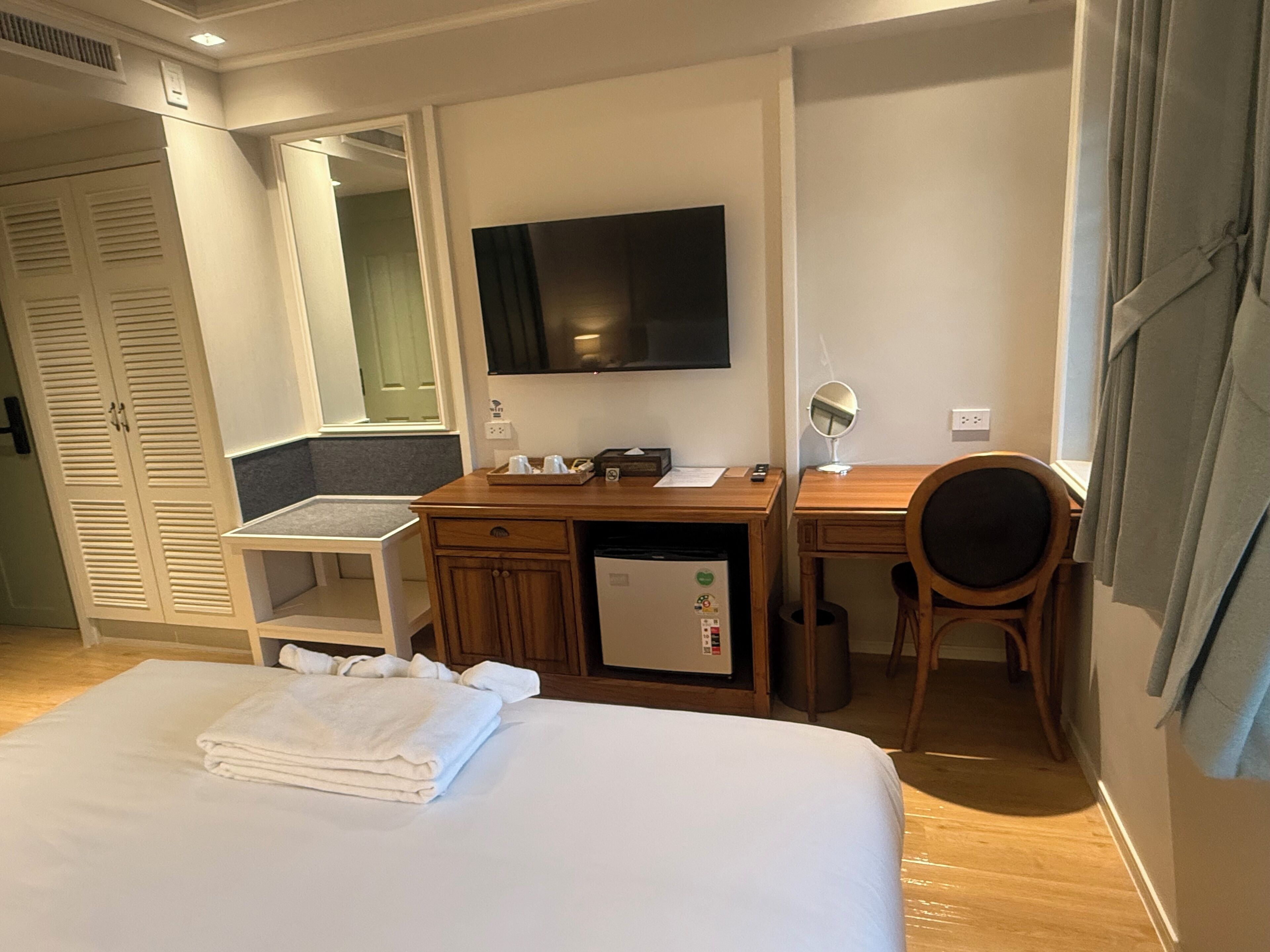Une chambre d’hôtel équipée d’un lit, d’un bureau, d’une chaise, d’une télévision, d’un miroir et d’une armoire.