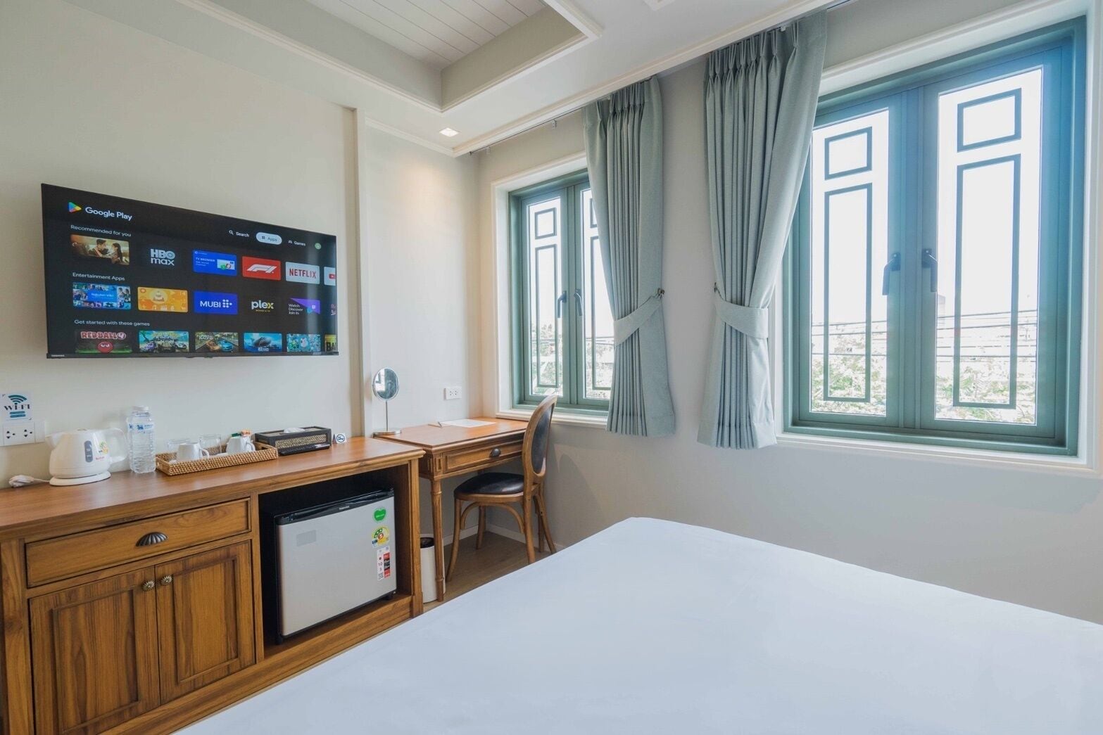 A hotel room with a bed, desk, chair, and a TV displaying streaming services.