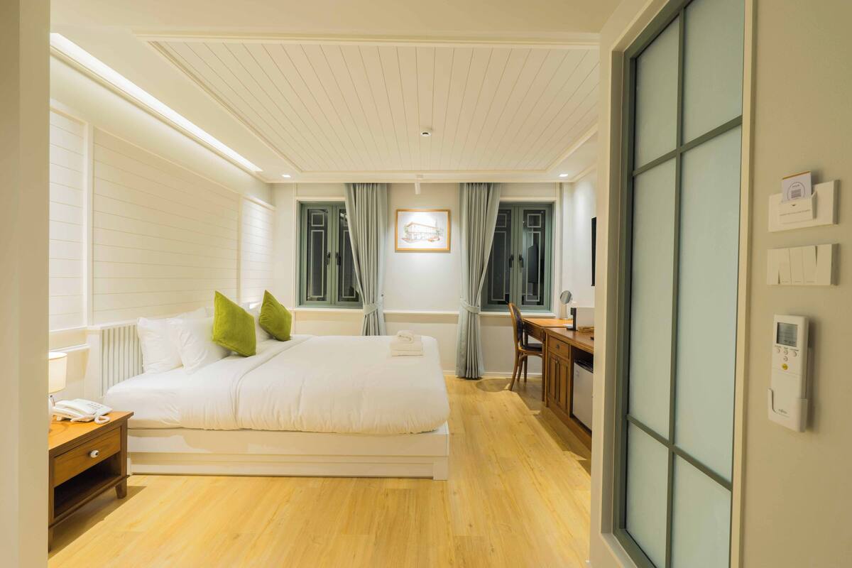 Une chambre d’hôtel avec un lit, une table de chevet, une lampe et une vue sur l’extérieur.
