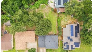 Vista aérea de una zona residencial con varias casas, céspedes verdes y árboles.