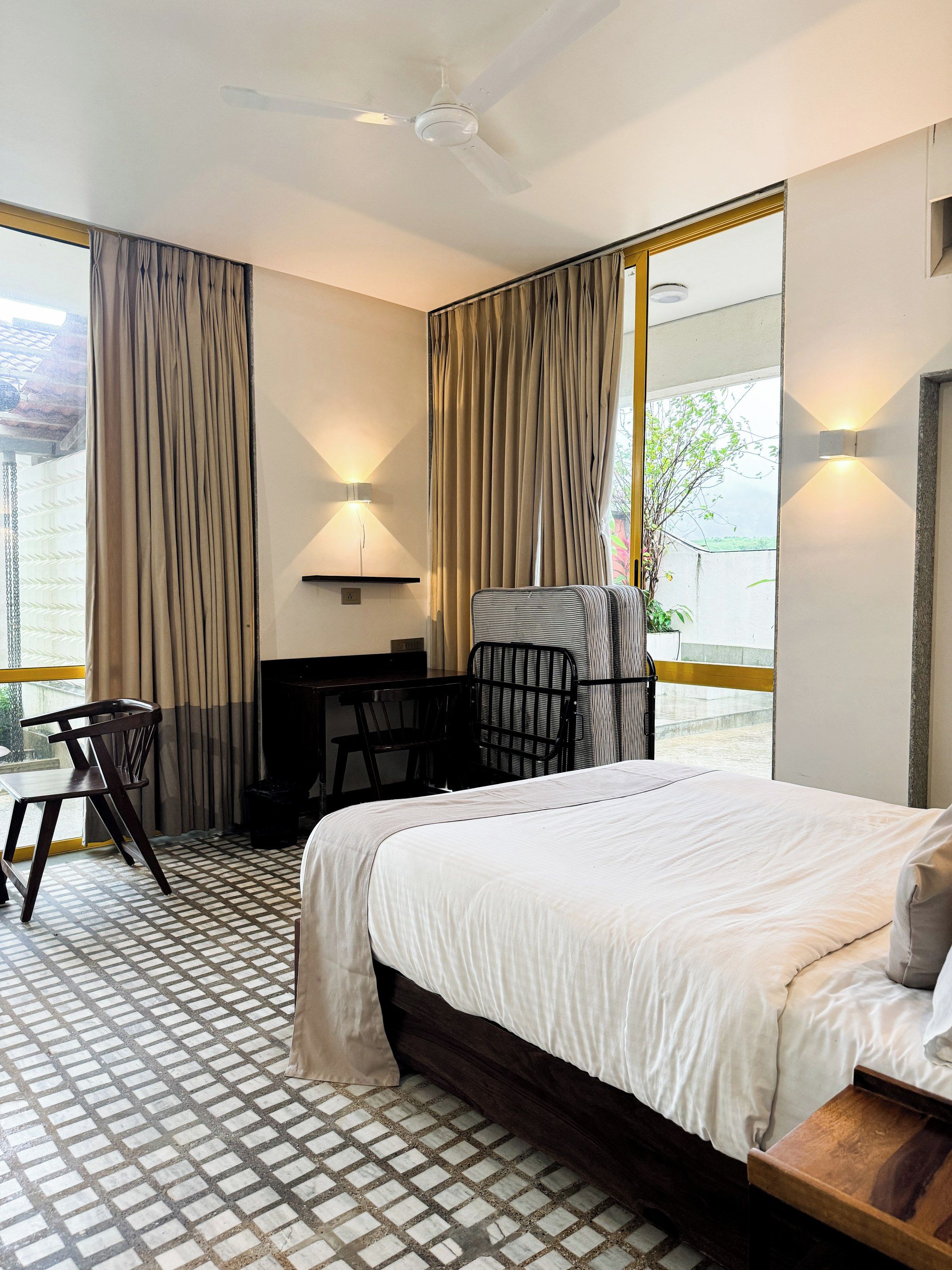 Habitación de hotel con una cama grande, un escritorio, una silla y vistas al exterior.