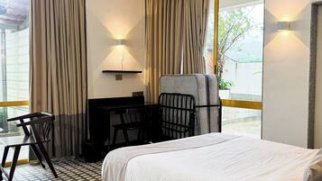 Habitación de hotel con una cama grande, un escritorio, una silla y vistas al exterior.