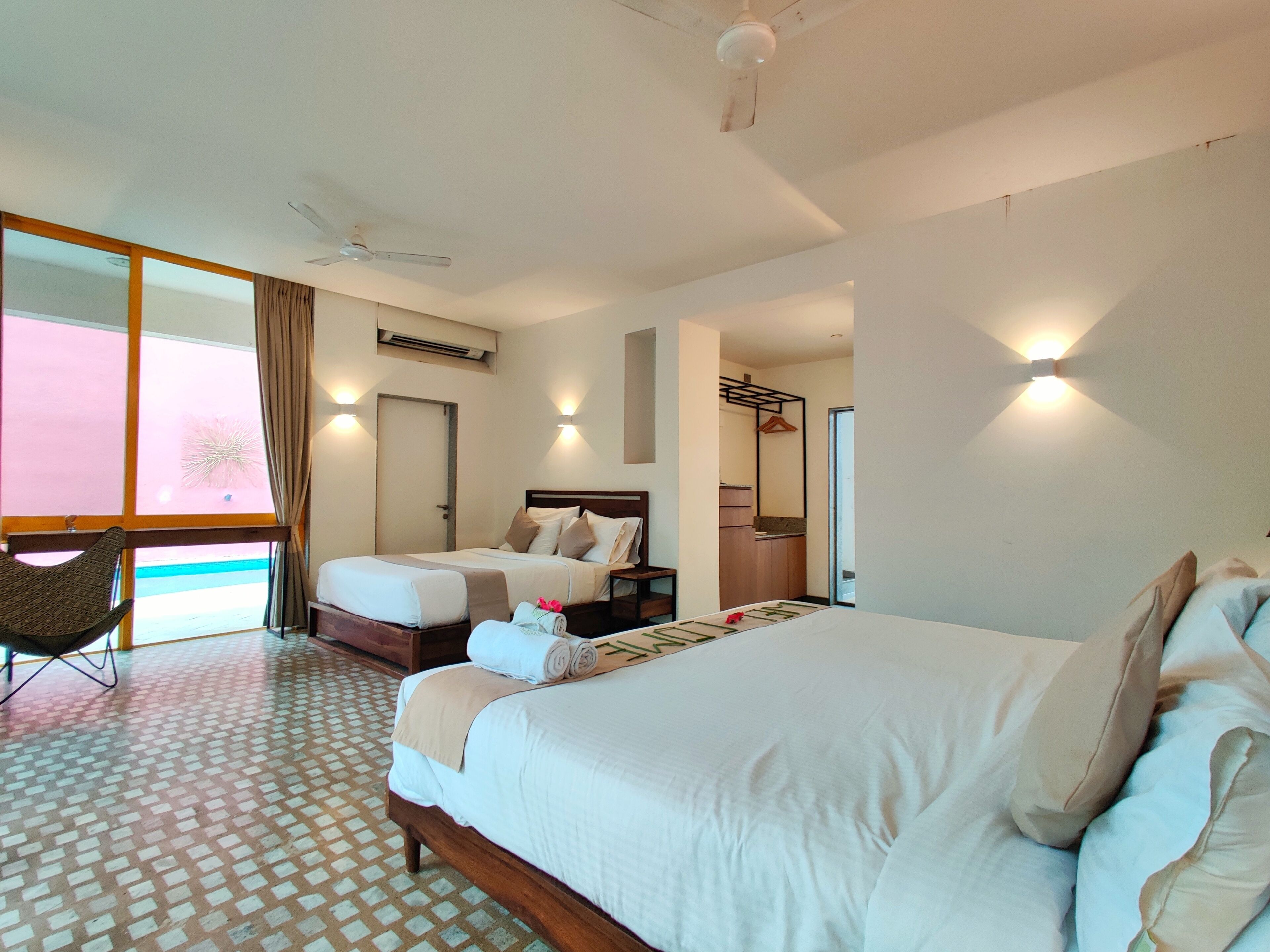 A hotel room with a large bed, a smaller bed, a chair, a desk, and a bathroom.
