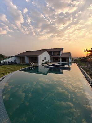Ein modernes Haus mit Swimmingpool, das Himmel und Wolken spiegelt.