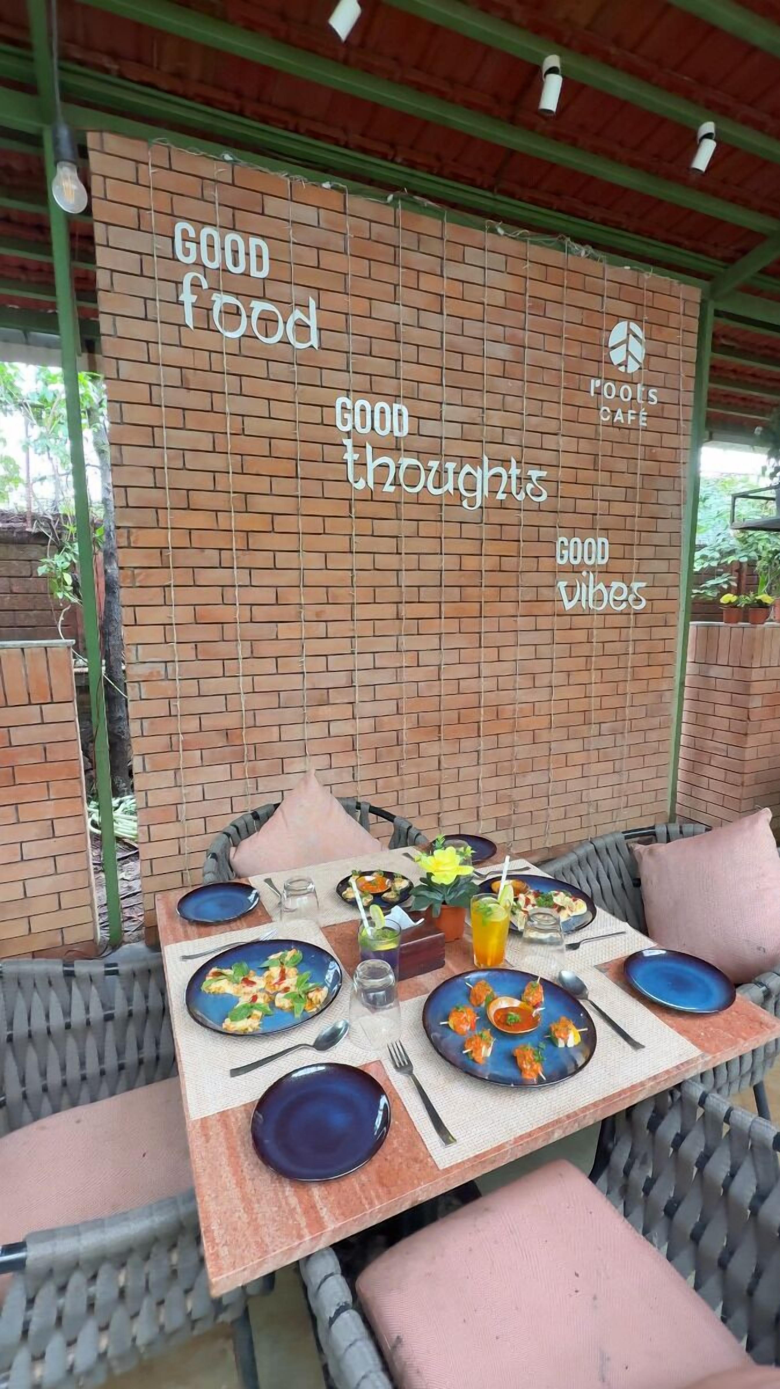 Een terras met een achtergrond van een bakstenen muur waarop motiverende zinnen staan, een gedekte tafel met eten en een ontspannen zithoek.