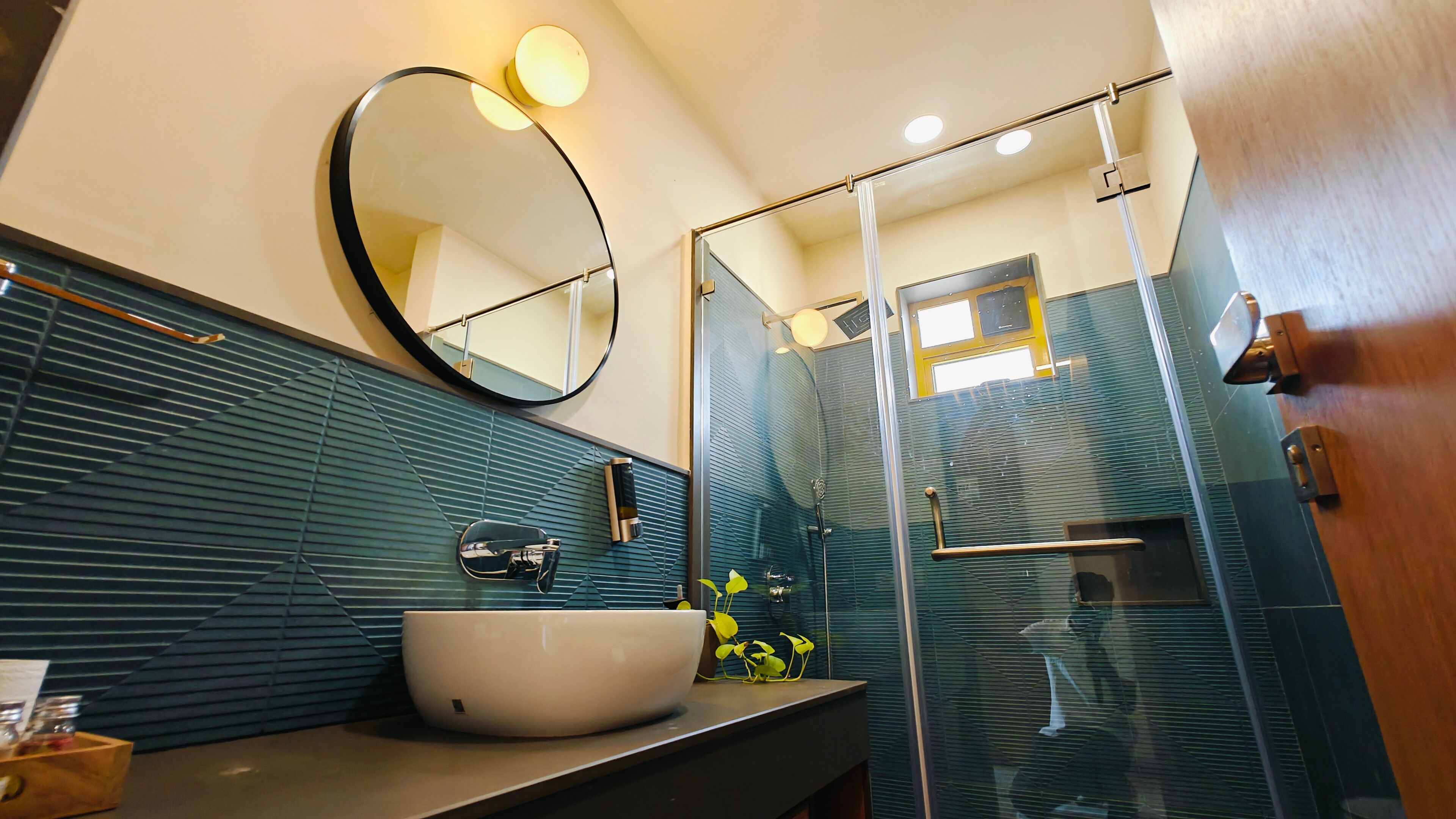 Un bagno moderno con uno specchio grande, un lavandino bianco e uno spazio doccia in vetro.