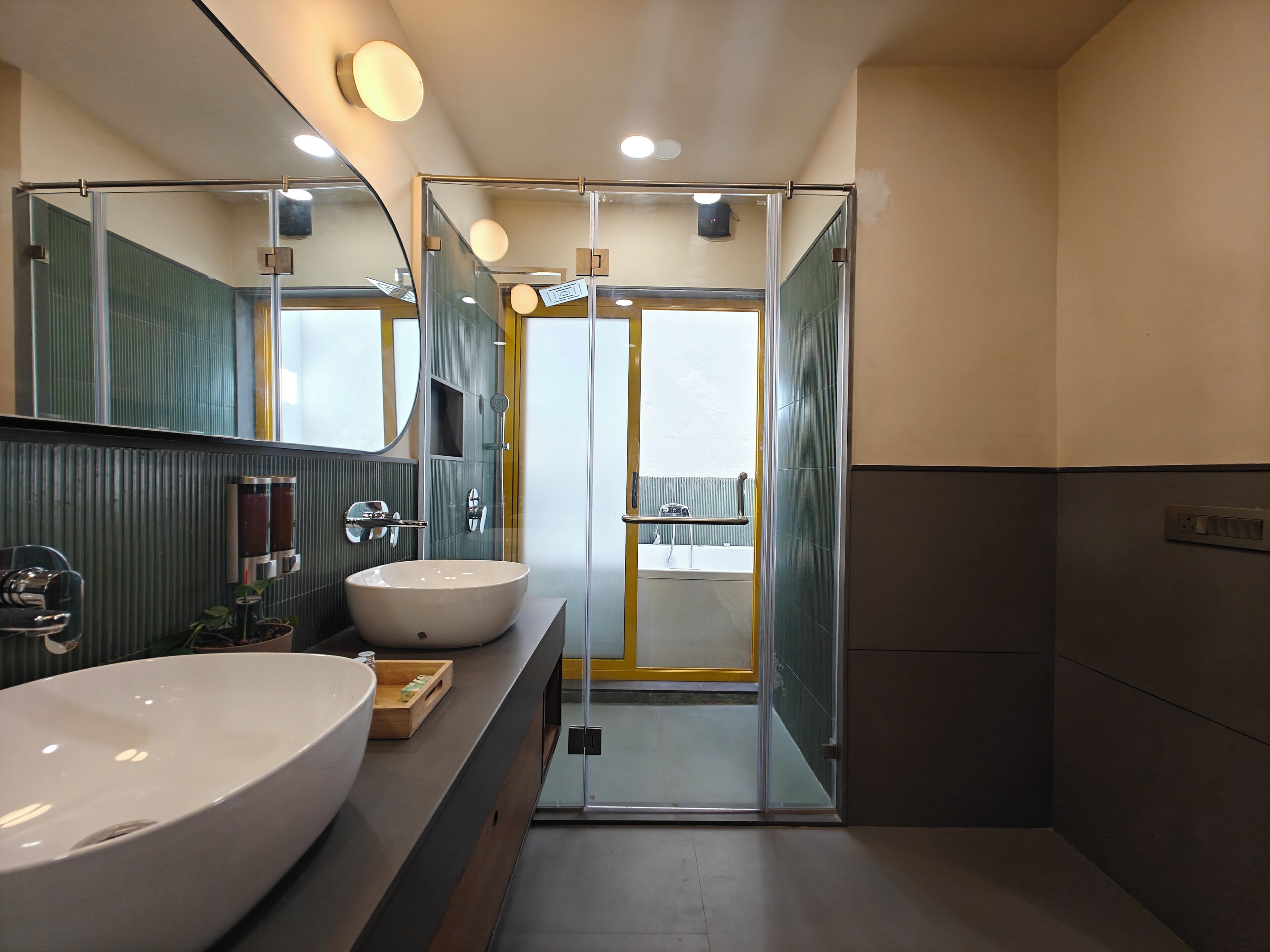 A modern bathroom with two large sinks, a glass shower enclosure, and a large mirror.