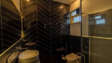 Ein modernes Badezimmer mit einem schwarz-weißen Fliesenmuster, einem weißen Waschbecken und einer Glasdusche.