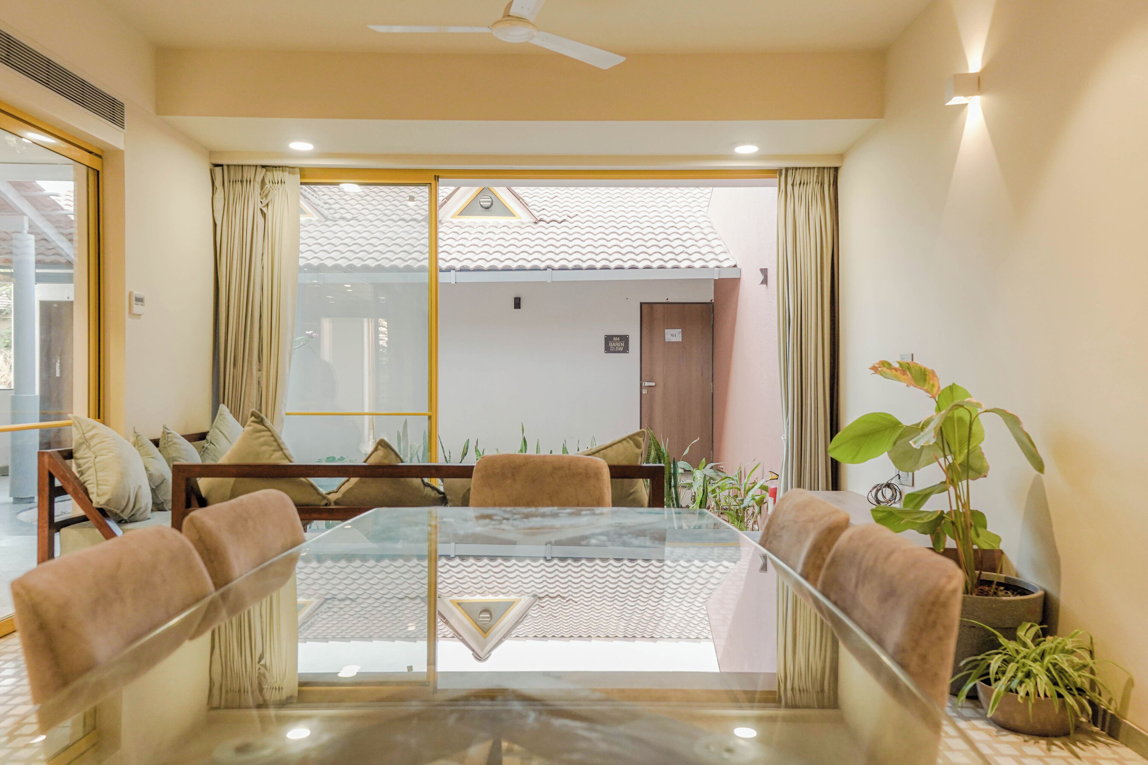 A modern meeting room with a glass table, comfortable seating, and potted plants.