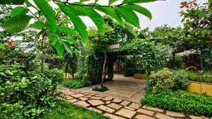 A garden pathway leading to a gazebo with a sign reading "Roots Cafe". - Touchwood Bliss Resort - Igatpuri (Igatpuri)