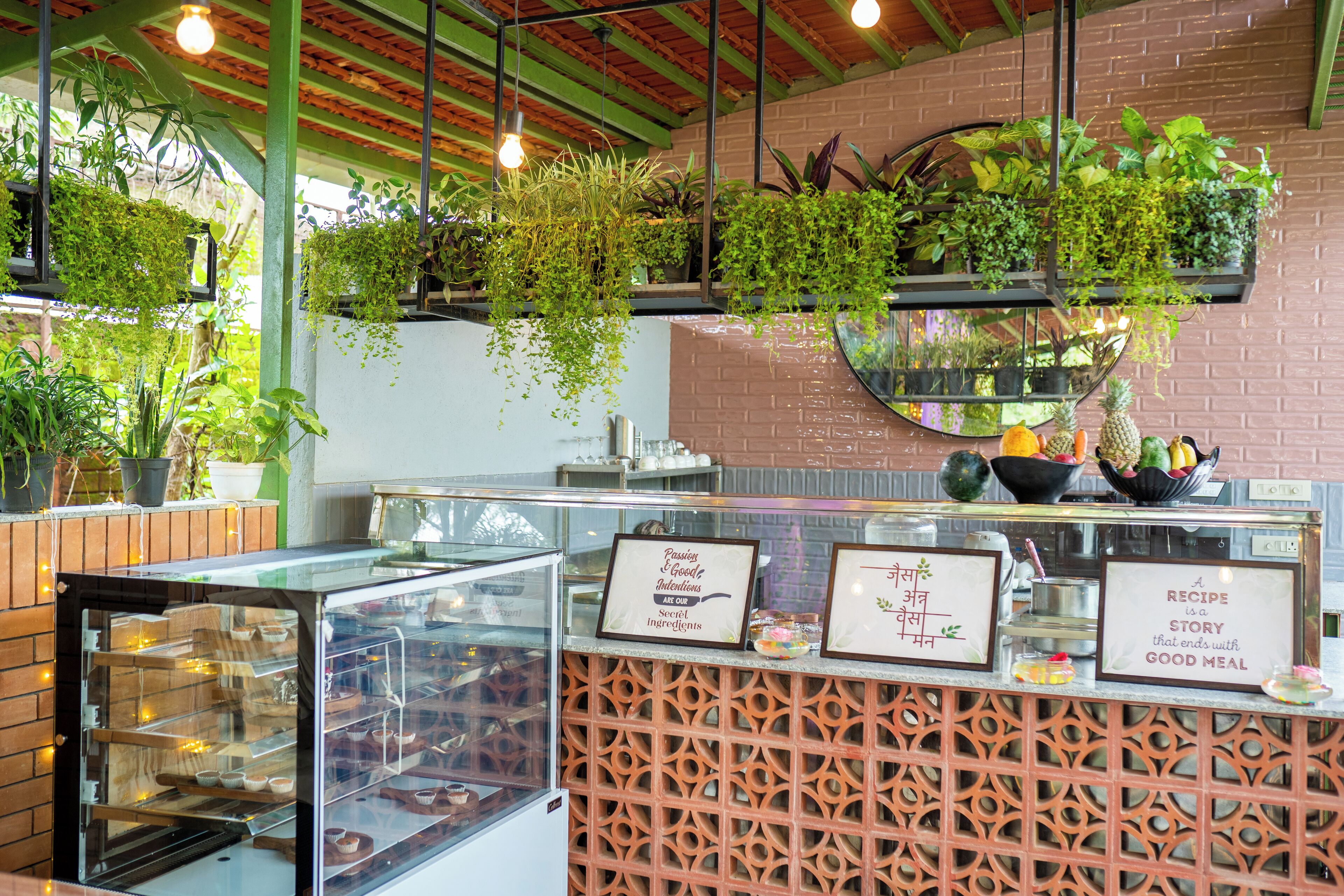A bakery counter with hanging plants, a display case, and framed signs.