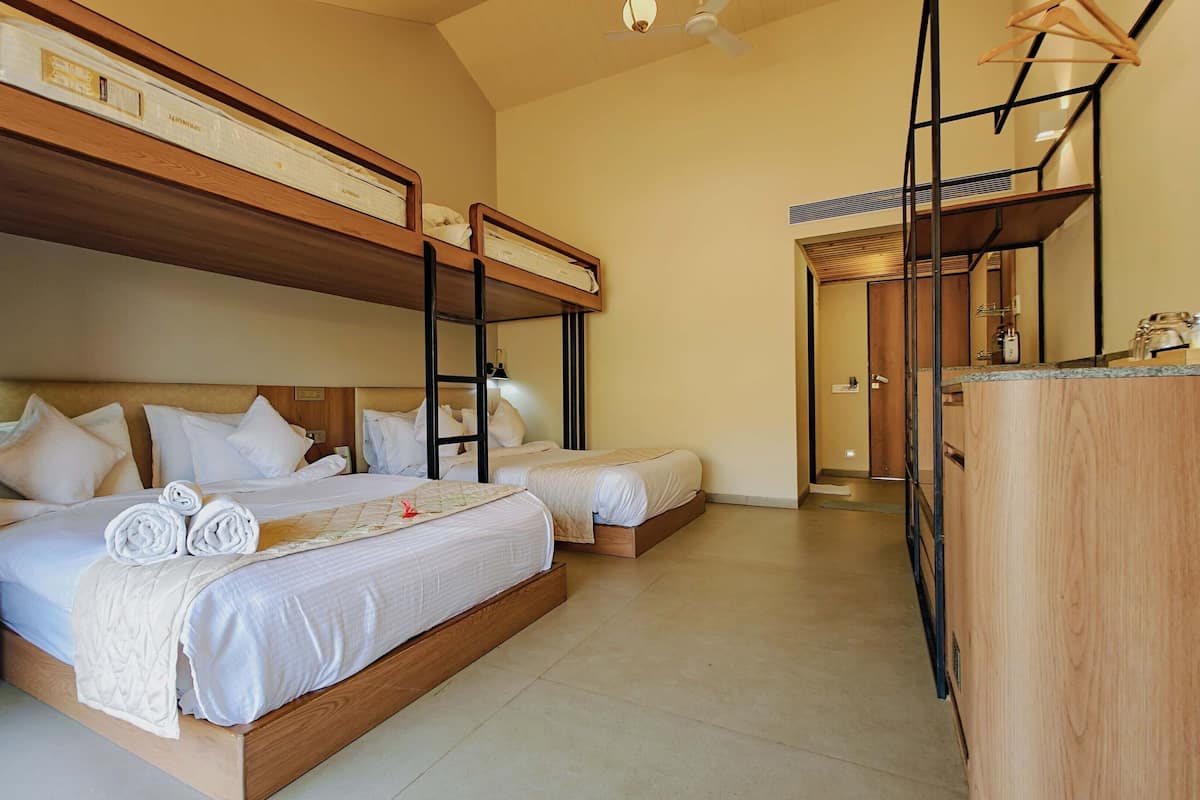 A hotel room with two beds, a wooden headboard, a desk, and a ceiling fan.