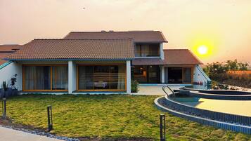 Una casa moderna con piscina, césped cuidado y cielo despejado.
