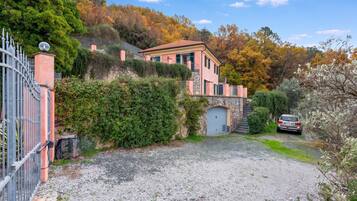 Une maison à deux étages avec une entrée surmontée d’un mur en pierre et une allée gravillonnée.