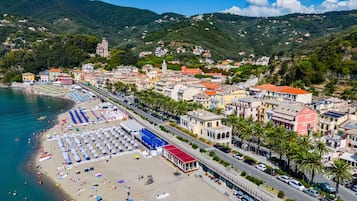 A coastal town with a beach, rows of beach umbrellas, and a mix of residential and commercial buildings.