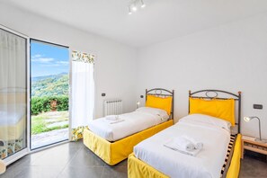 Habitación de hotel con dos camas, vista a un paisaje montañoso y puerta corredera de vidrio.