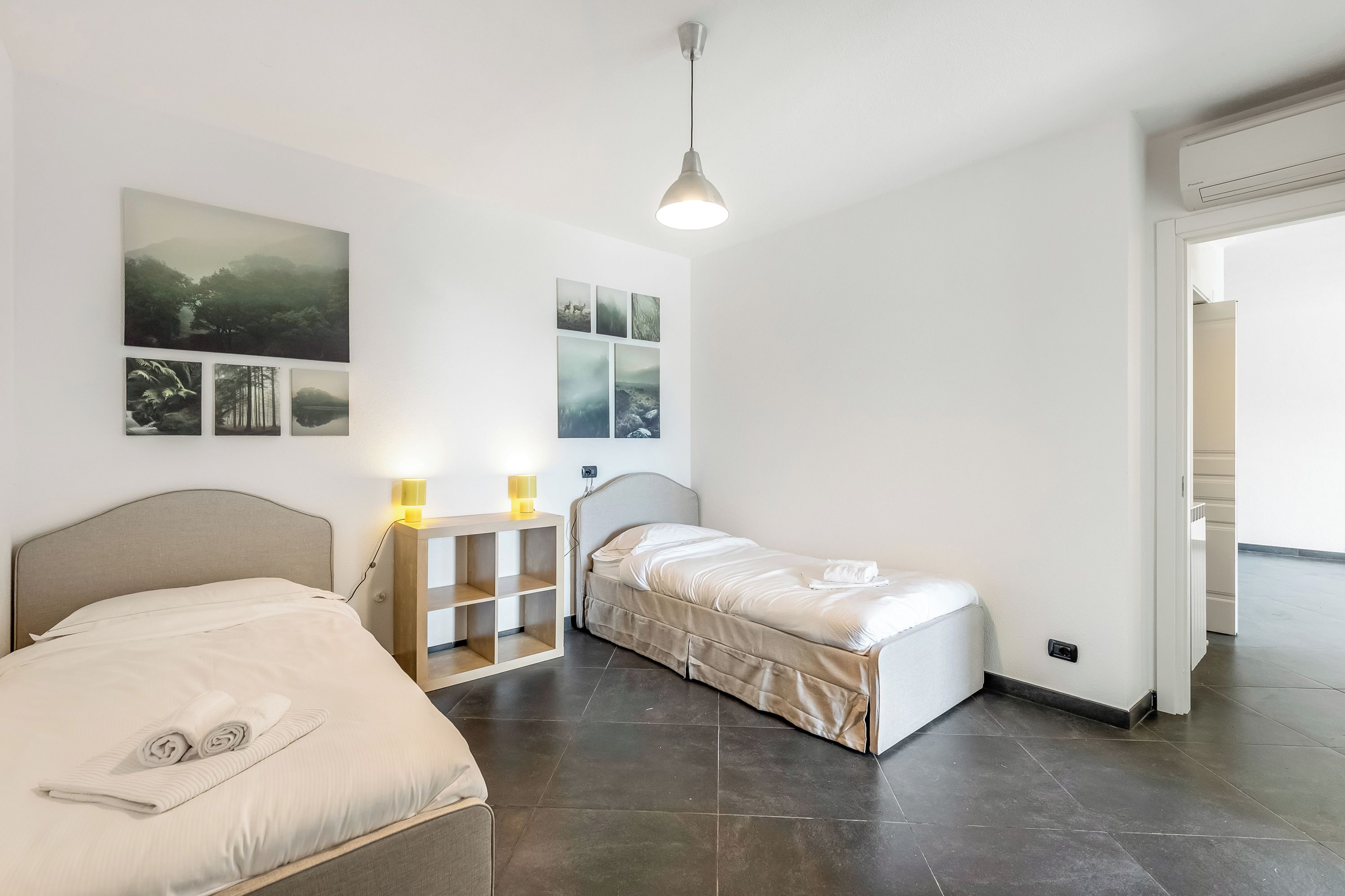 A bedroom with a bed, bedside table, lamp, and wall art.