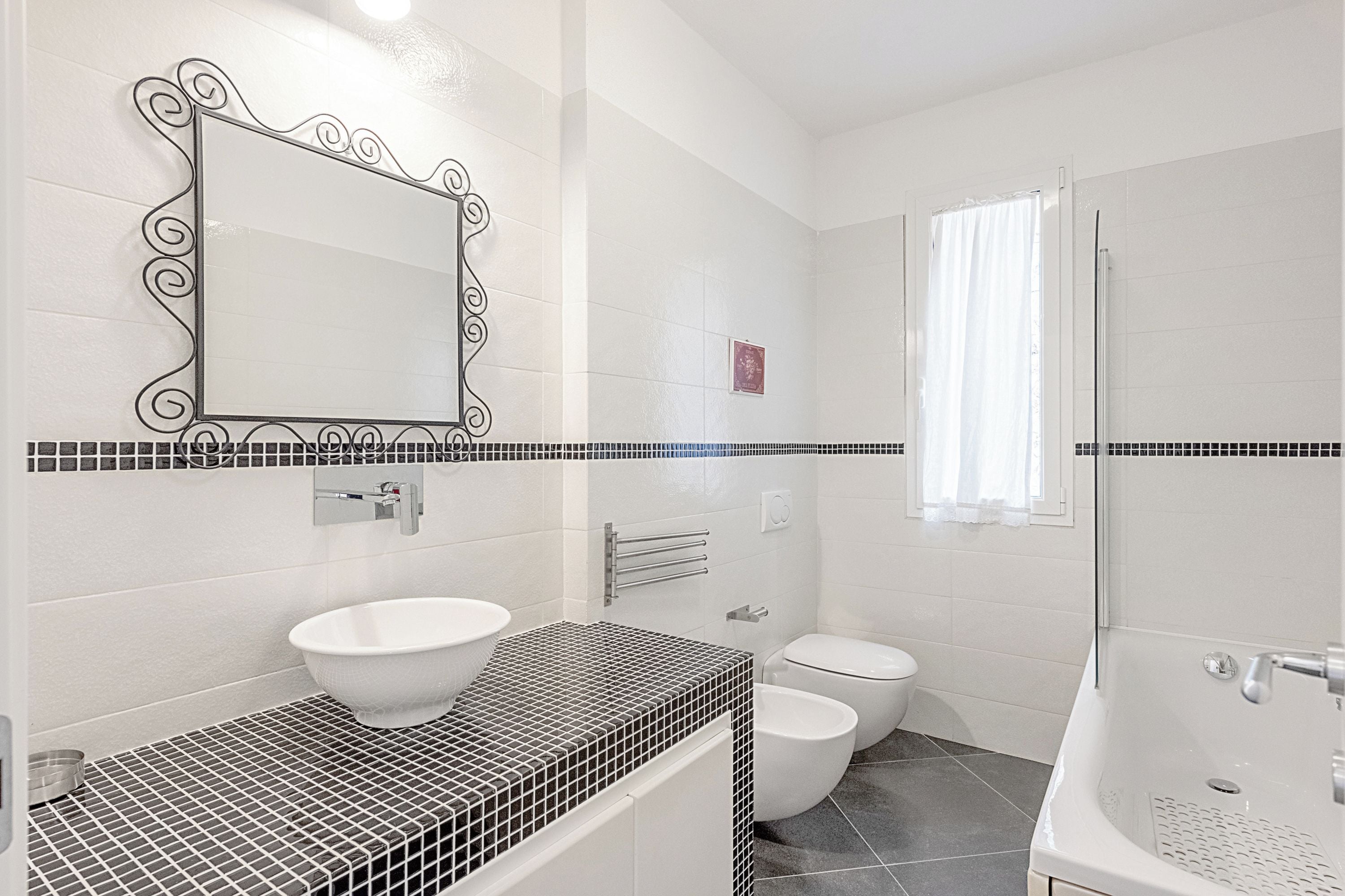 Et badeværelse med en hvid vask, toilet og badekar.