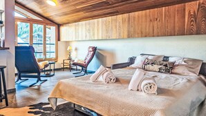 Una habitación acogedora con techo de madera, una cama con toallas enrolladas, una silla y vistas al exterior.