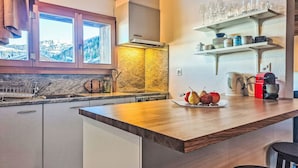 Una cocina moderna con encimera de madera, pileta integrada y ventana con vistas a un paisaje montañoso.