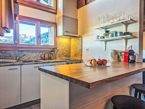 Eine moderne Küche mit einer Holztresen, einer integrierten Spüle und einem Fenster mit Blick auf eine Berglandschaft.