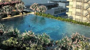 Una piscina con vista sul mare, circondata da vegetazione e edifici moderni.