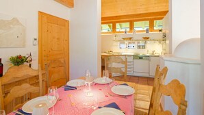 A dining area with a red and white checkered tablecloth, wooden chairs, and a wooden ceiling. - Talschluss 500 by Interhome (Saalbach-Hinterglemm)