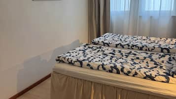 Ein Hotelzimmer mit Bett, einem Fenster mit Vorhängen, einem Wandbild und Holzboden.