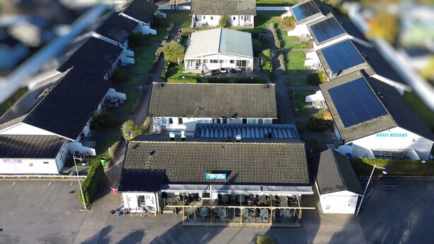 An aerial view of a hotel with multiple buildings, solar panels on the roofs, and a parking lot. - Åhus Havsvillor (Aahus)