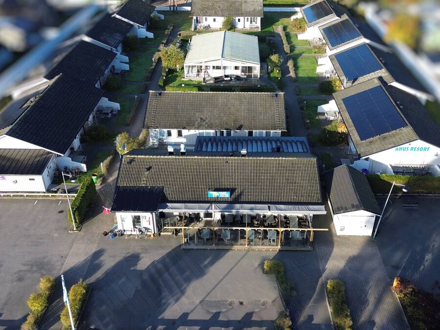 An aerial view of a hotel with multiple buildings, solar panels on the roofs, and a parking lot.