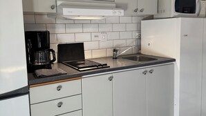 A kitchen with white cabinets, a microwave, a coffee maker, and a gas stove. - Åhus Havsvillor (Aahus)