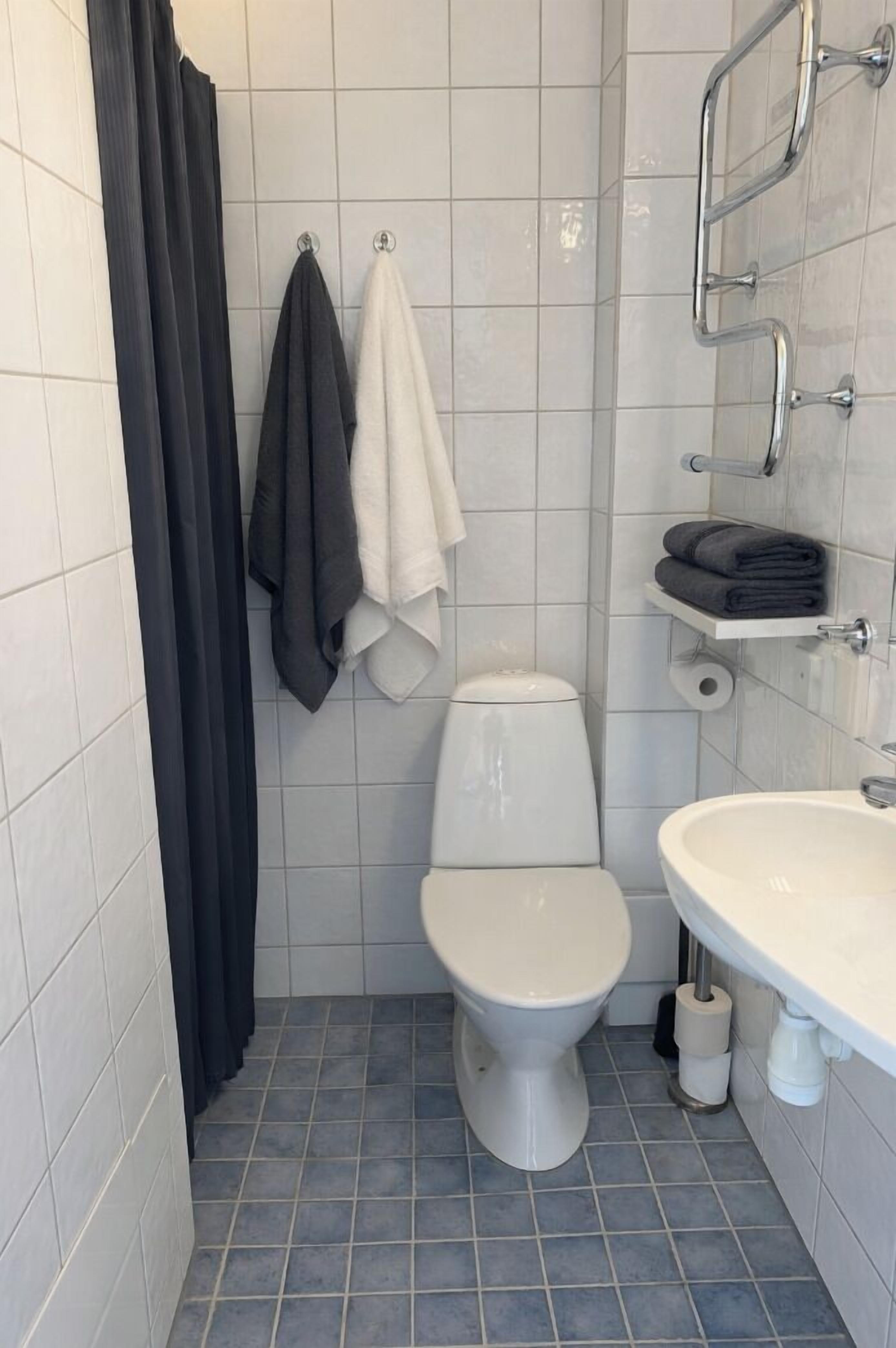 A bathroom with a toilet, a sink, a towel rack, and a shower curtain.