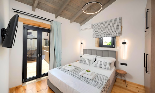 A bedroom with a bed, a TV, a window, and a ceiling fan.