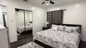 Ein Schlafzimmer mit Bett, Deckenventilator, Spiegel und Nachttisch.