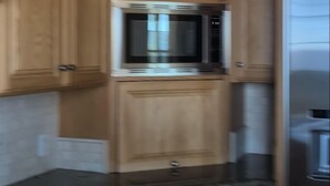 Una cocina con armarios de madera, microondas integrado y refrigerador de acero inoxidable.