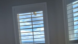 Un baño con bañera, una ventana con persianas y vistas al exterior.