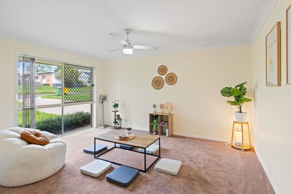 A modern living room with a white sofa, a coffee table, and a floor lamp. - Riverview Modern Haven | Entire 4BR Home (Riverview)