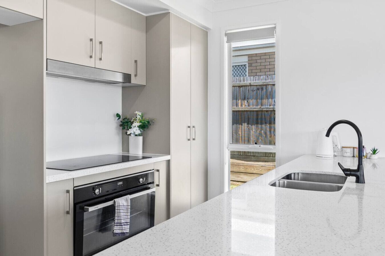 A modern kitchen with stainless steel appliances, a white countertop, and a black faucet.