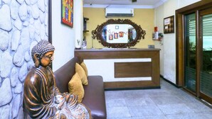 A reception area with a Buddha statue, a reception desk, a mirror, and a ceiling fan. - Say Moments (Kolkata)