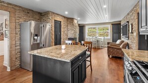 A kitchen with a stone accent wall, a large island, and a dining area with a view.