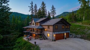 A two-story log cabin with a stone foundation, a balcony, and a garage.