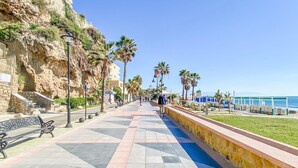 A coastal promenade with a tiled walkway, benches, palm trees, and a view of the sea. - Apartment in Torremolinos Near Bajondillo Beach (Torremolinos)