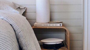 A neatly arranged corner with a white vase, a book titled 'Home by the Sea', and a wicker basket on a shelf. - Skippers Hideaway - A Peaceful Coastal Escape (The Entrance North)