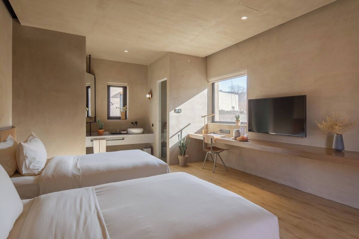 Une chambre moderne avec deux lits, un bureau, une tél évision et une salle de bain.