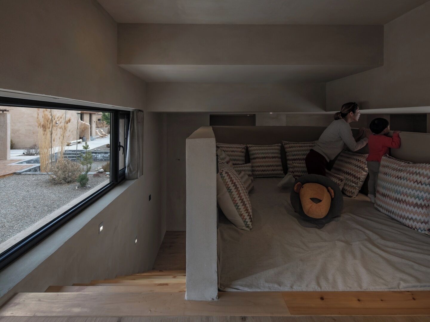 A modern interior with a sofa bed, a window with a view of the outside, and a staircase leading to an upper level.