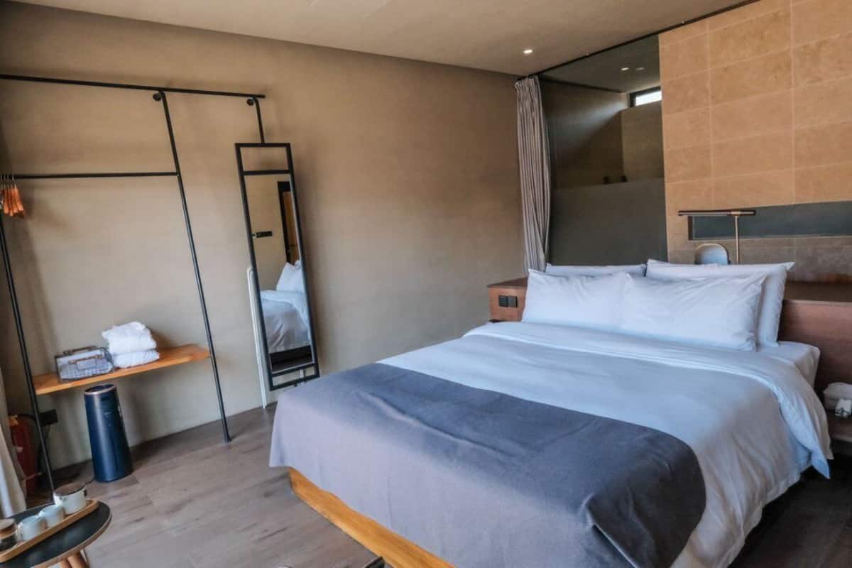 Une chambre d’hôtel moderne avec un grand lit, une table de chevet, un miroir et une armoire.
