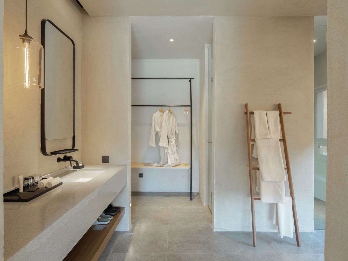 Un baño moderno con un espejo grande, un tocador con lavamanos y un perchero para toallas.